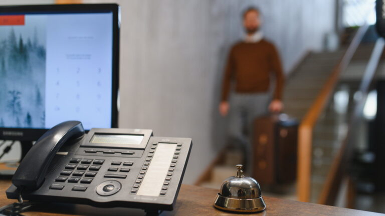 Office desk phone on a front counter with a customer waiting in the background