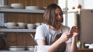 Small business owner checking her Google Business Profile on her phone in her studio