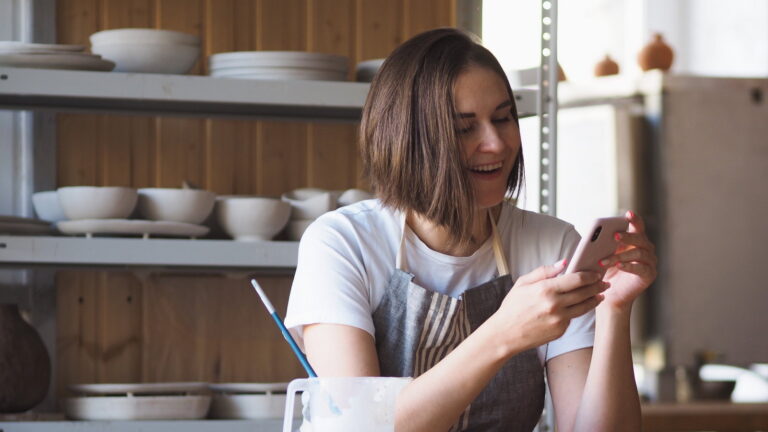 Small business owner checking her Google Business Profile on her phone in her studio