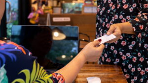 Customer handing a card across the counter to a shop owner working at a tablet