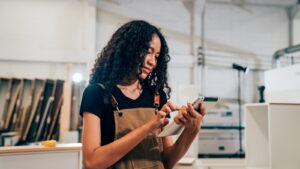 Small business owner writing a Google Business Profile post on her tablet in her workshop